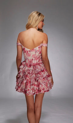 A woman with long blonde hair models the Alyce 30034 short homecoming dress, an off-the-shoulder pink floral fit-and-flare style, shown from the back against a plain gray background.