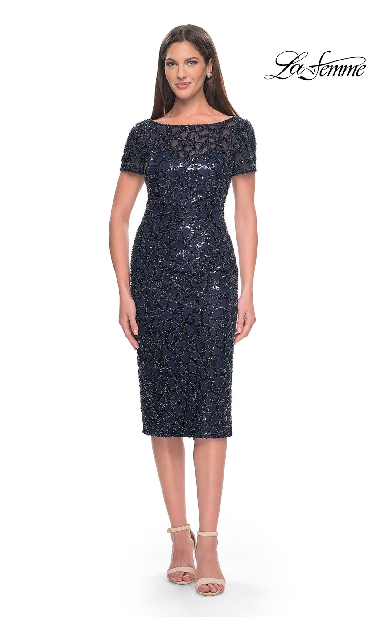 A woman wears a navy Knee Length Wedding Guest Dress: La Femme 30043, a knee-length sheath dress featuring short sleeves, a sheer neckline, and all-over sequin and bead embellishment.