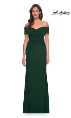 A woman wears the Long Formal Dress: La Femme 30057 in emerald, an off-the-shoulder, floor-length gown with ruched details and beaded short sleeves.