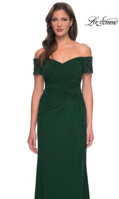 A woman in the Long Formal Dress: La Femme 30057, dark green with ruched bodice and beaded short sleeves, poses gracefully against a white background.