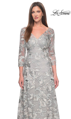 A woman wears a grey, V-neck La Femme 30062 long formal dress with three-quarter sleeves and intricate silver floral embroidery.