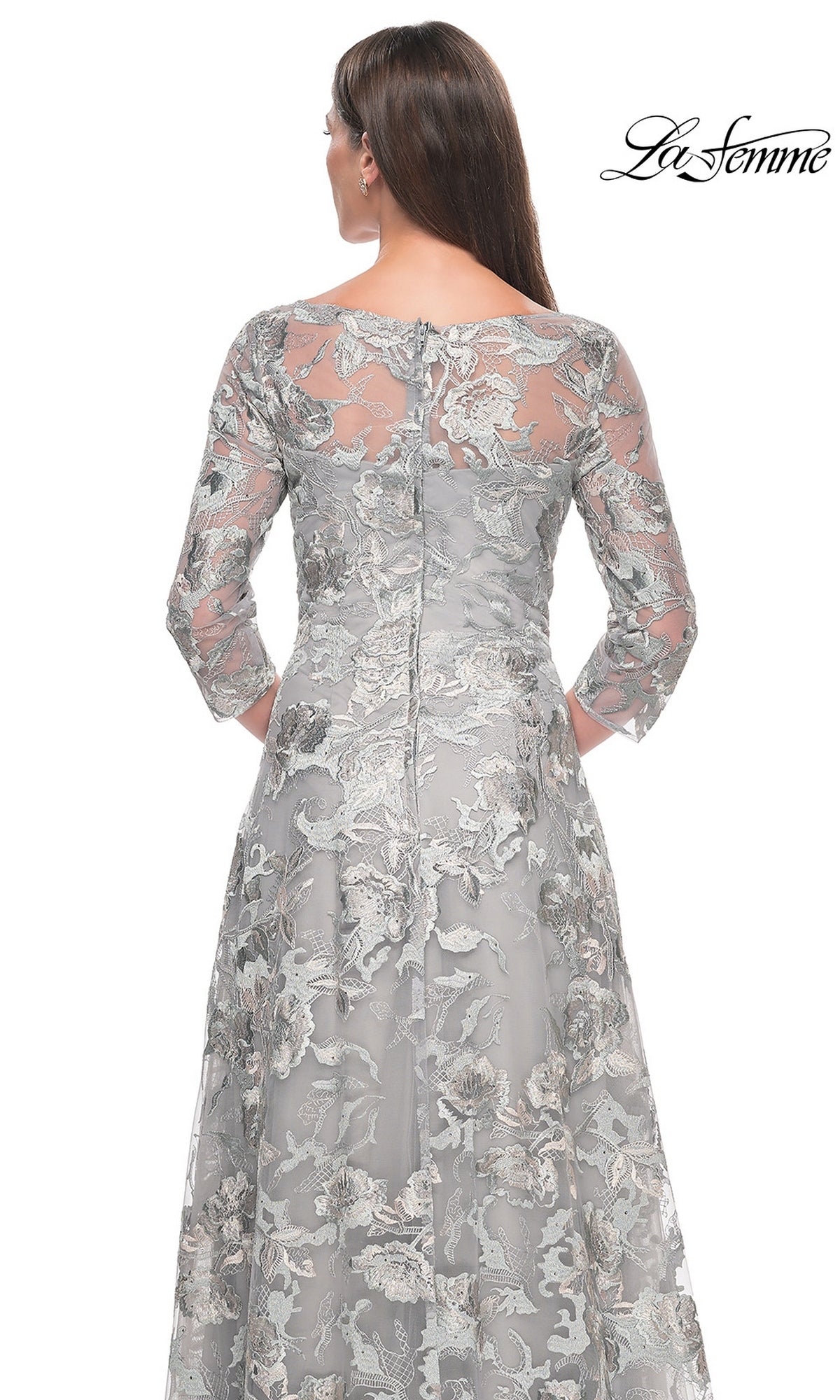 Back view of a grey, three-quarter sleeve La Femme 30062 formal dress featuring an all-over floral lace overlay and a knee-length A-line skirt.
