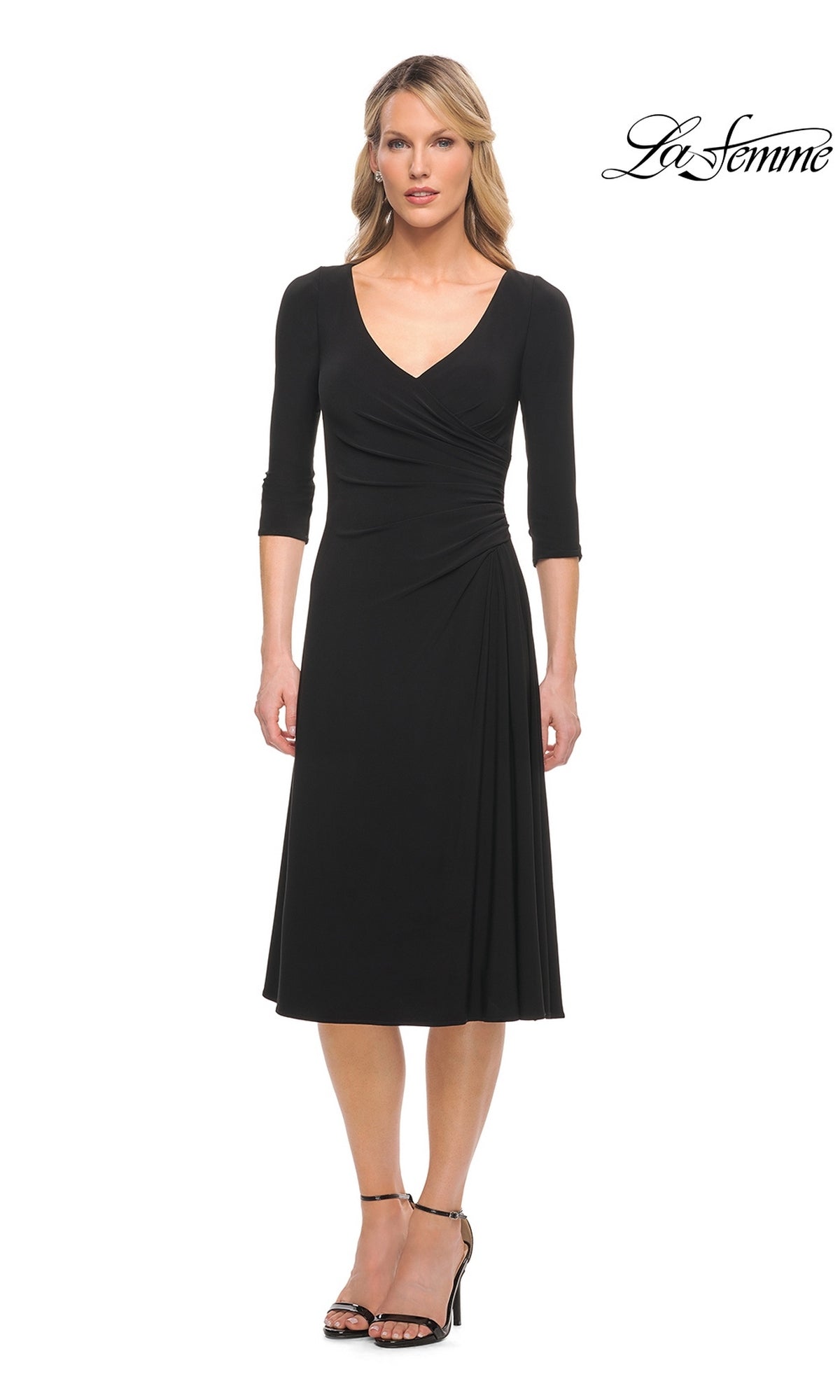 A woman wears the black Midi Wedding Guest Dress: La Femme 30069, a fit-and-flare jersey dress with a V-neck, three-quarter length sleeves, and gathered detailing at the waist.