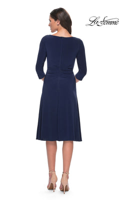 A woman seen from behind wearing a navy blue, midi-length, fit-and-flare Midi Wedding Guest Dress: La Femme 30069 and nude high-heeled pumps.
