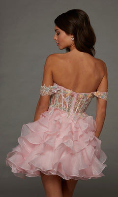 A woman wearing the Alyce 30087 Short Homecoming Dress—an off-shoulder, fit-and-flare pink mini dress featuring a ruffled skirt and beaded floral appliques on the bodice—stands facing away while glancing to the side against a plain background.