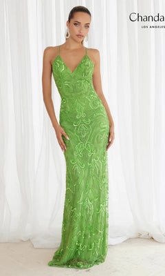 A woman in the Sequin-Print Long Prom Dress: Chandalier 30087, a fitted, floor-length green gown with sequin detailing, stands before white curtains.