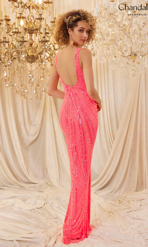 A woman with curly hair wears the Long Prom Dress 30091 by Chandalier, a fitted pink sequin gown with an open back, standing before chandeliers and draped white fabric.