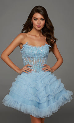A woman stands with hands on hips against a plain gray background, modeling the Glacier Blue Alyce 30094 short homecoming dress featuring ruffles, floral embellishments, and a sheer lace corset bodice.