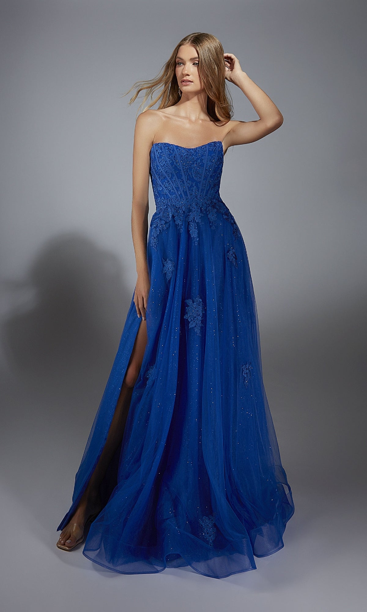 A woman models the Long Prom Dress: Aerie Couture 300—royal blue, strapless, with a corset bodice, side slit, and floral embellishments—against a plain grey background.