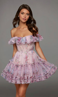A woman wearing the Alyce 30103 short homecoming dress in lilac/multi, featuring a fit-and-flare silhouette with off-the-shoulder sleeves and sheer bodice details, stands against a plain grey background.