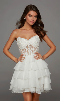 A woman models the Alyce 30109 Short Homecoming Dress in Diamond White, showcasing its strapless design with 3D floral appliques on the bodice and a layered ruffled skirt, as she stands with hands on hips against a plain background.