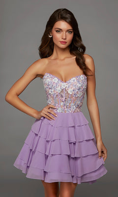 Dressed in the Alyce 30109 short homecoming dress in lilac, a woman stands against a plain gray background. The strapless fit-and-flare dress features a tiered skirt and bodice detailed with intricate 3D floral appliques.