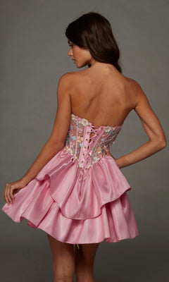 A woman models the Alyce 30114 short homecoming dress—a pink strapless fit-and-flare style featuring a lace-up back, floral-embroidered bodice, and layered satin skirt. She turns her head to the side against a plain background.