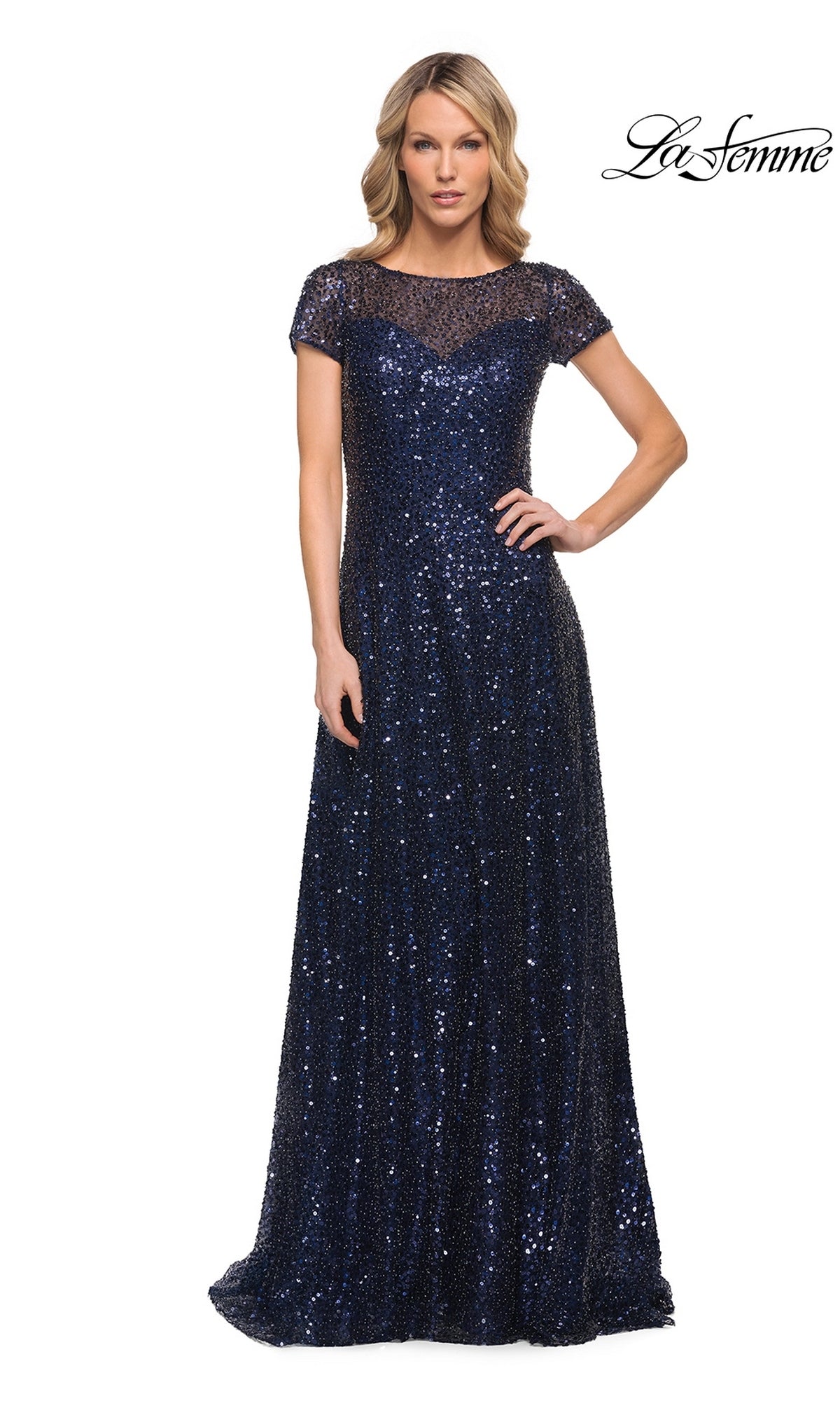 A woman wears the Long Formal Dress: La Femme 30122, a floor-length, navy blue sequin formal dress with cap sleeves, an A-line silhouette, and a sheer illusion neckline.
