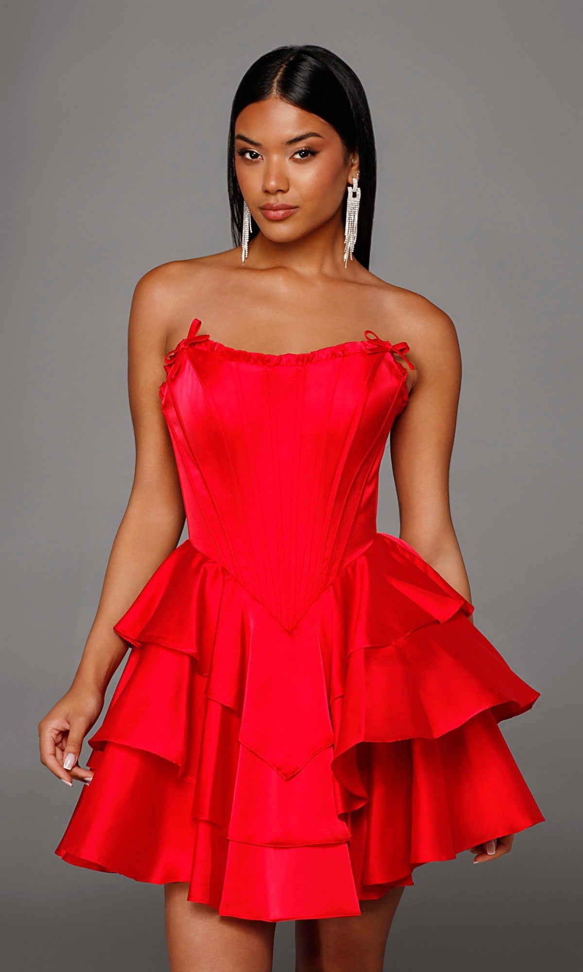 Model showcases the Alyce 30123 Short Homecoming Dress, a strapless satin design with a structured corset bodice and a tiered, bright red ruffled skirt, set against a plain gray background.