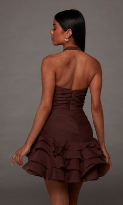 A woman stands facing away against a plain gray background, wearing the Alyce 30127 Short Homecoming Dress—a strapless, brown ruffled crinkle organza design.