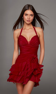 A woman stands against a plain gray background wearing the Alyce 30127 short homecoming dress—a sleeveless, halter-neck design crafted from red crinkle organza, featuring ruffled layers and a floral detail at the waist.