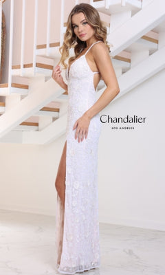 A woman in the Chandalier 30131 long prom dress, featuring white floral motifs, a sleeveless design, and a high-leg slit, stands by a staircase with "Chandalier Los Angeles" displayed beside her.