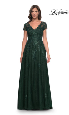 A woman wearing a floor-length, emerald green lace La Femme 30168 formal dress with short sleeves and a V-neckline.