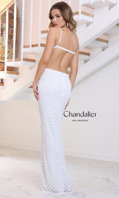 A woman stands indoors near a staircase, facing away in the Long Prom Dress: Chandalier 30211. The white, open back gown features hot stone embellishments. "Chandalier Los Angeles" appears beside her.