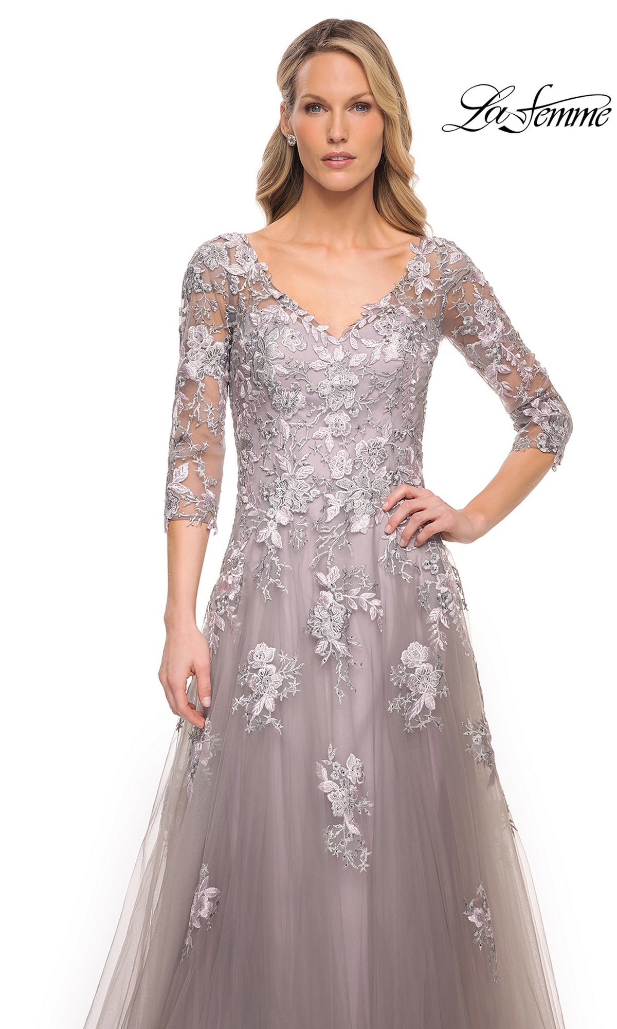 A woman wears a long, gray La Femme 30229 mother of the bride gown with three-quarter sleeves and silver floral embroidery.
