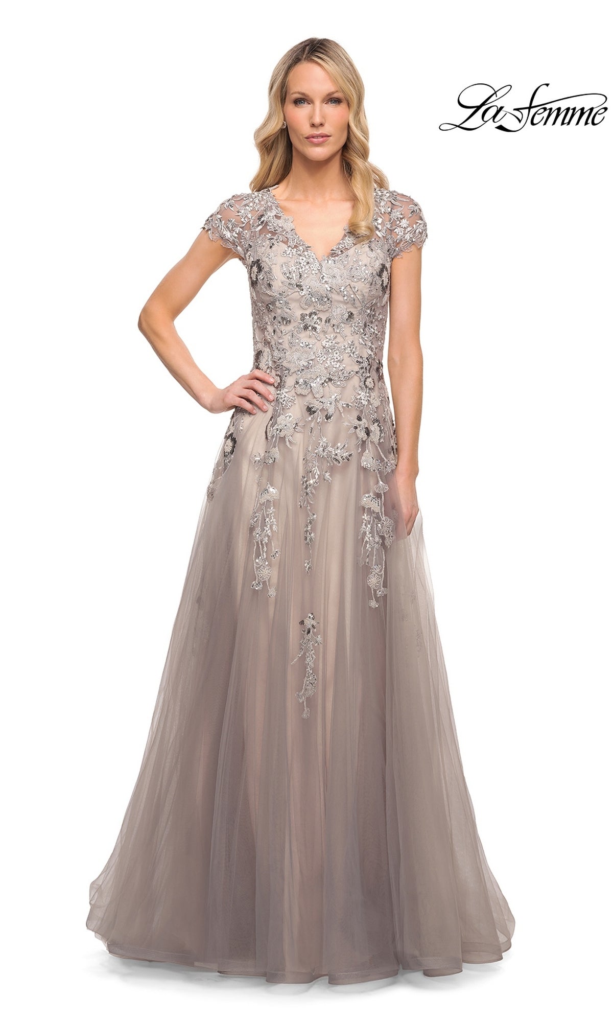 A woman wears the Long Formal Dress: La Femme 30239, a silver and pink tulle gown with cap sleeves and silver floral embroidery on the bodice and skirt.