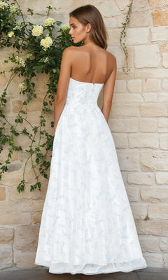 A woman in the Blondie Nites 3024BN long formal dress stands with her back to the camera against a stone wall covered in green leaves and white flowers.