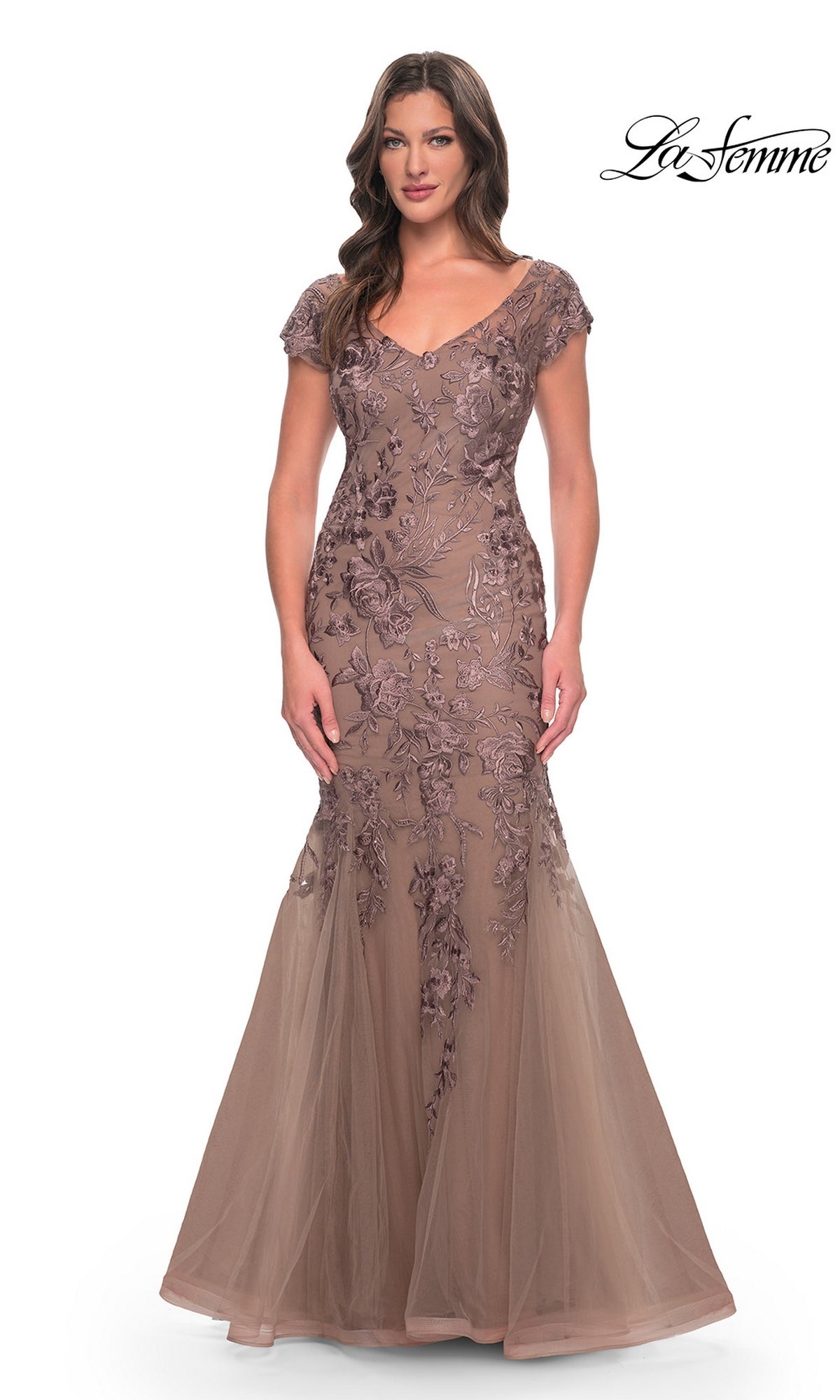 A model wears a cocoa-colored, floor-length Long Formal Dress: La Femme 30269 mermaid gown with a V-neckline, cap sleeves, and floral embroidery.