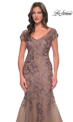 A woman wearing the Long Formal Dress: La Femme 30269, a taupe, v-neckline floor-length mermaid gown with cap sleeves and floral lace embroidery throughout the bodice and skirt.