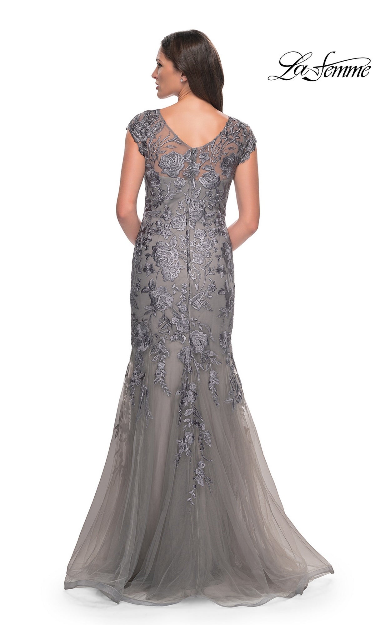 A woman seen from behind wearing a La Femme 30269 grey, floor-length, cap-sleeve mermaid dress with floral embroidery and a tulle skirt.