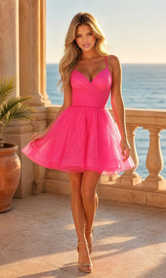 A woman stands on a stone terrace by the ocean, sunlight highlighting her Neon Pink La Femme Short Babydoll Homecoming Dress and the scenic backdrop.