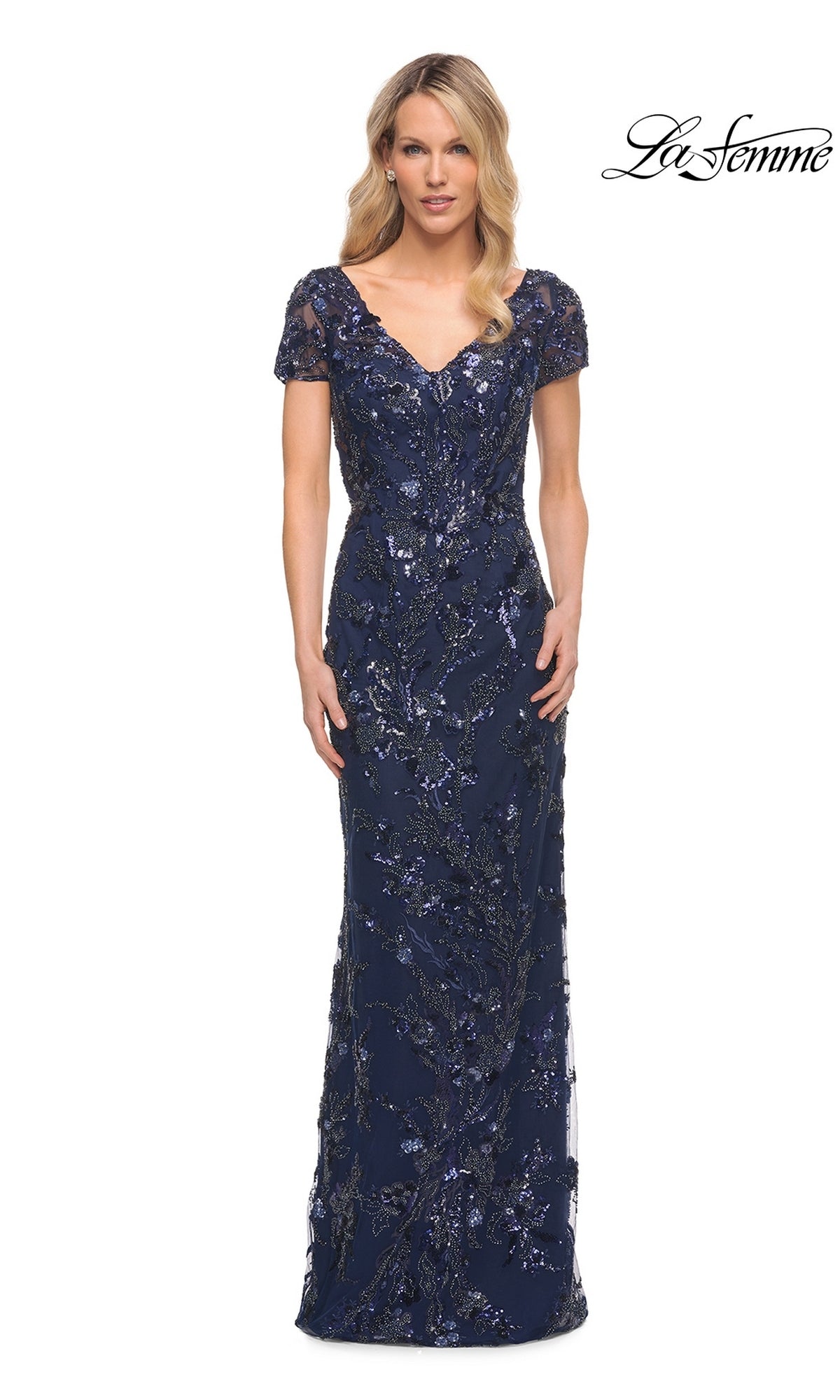 A woman wearing a navy blue, short-sleeved, floor-length La Femme 30375 gown featuring an all-over sequin and floral pattern suitable for evening weddings.