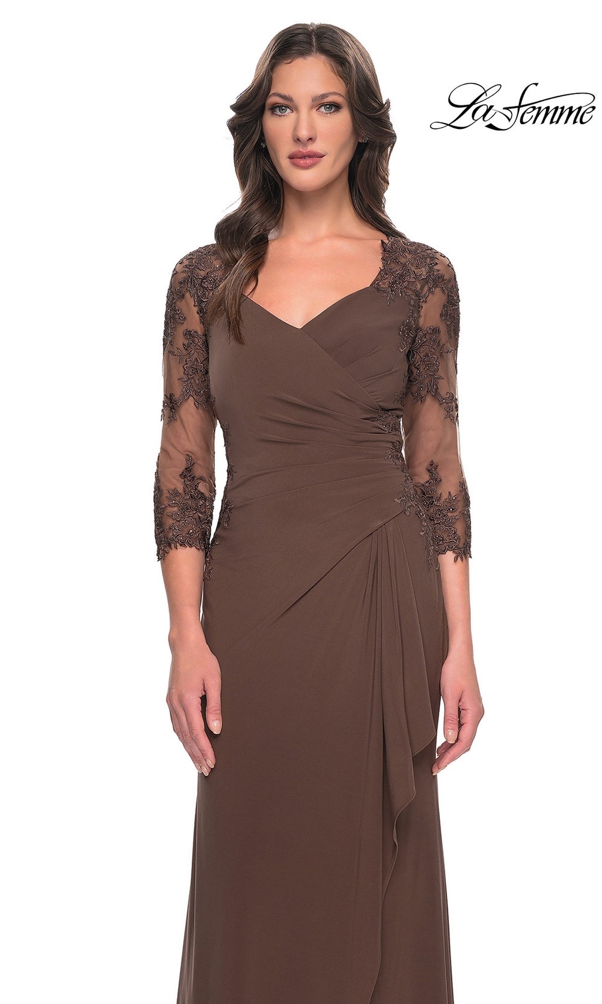 A woman models the Long Formal Dress: La Femme 30384, featuring sheer lace sleeves and a wrap-style bodice, in an elegant long brown gown against a white background.