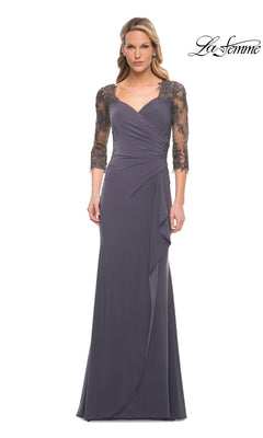 A woman wears the Long Formal Dress: La Femme 30384 in gunmetal with sheer lace 3/4 sleeves, a ruched bodice, and draped skirt. “La Femme” logo is in the top right corner.