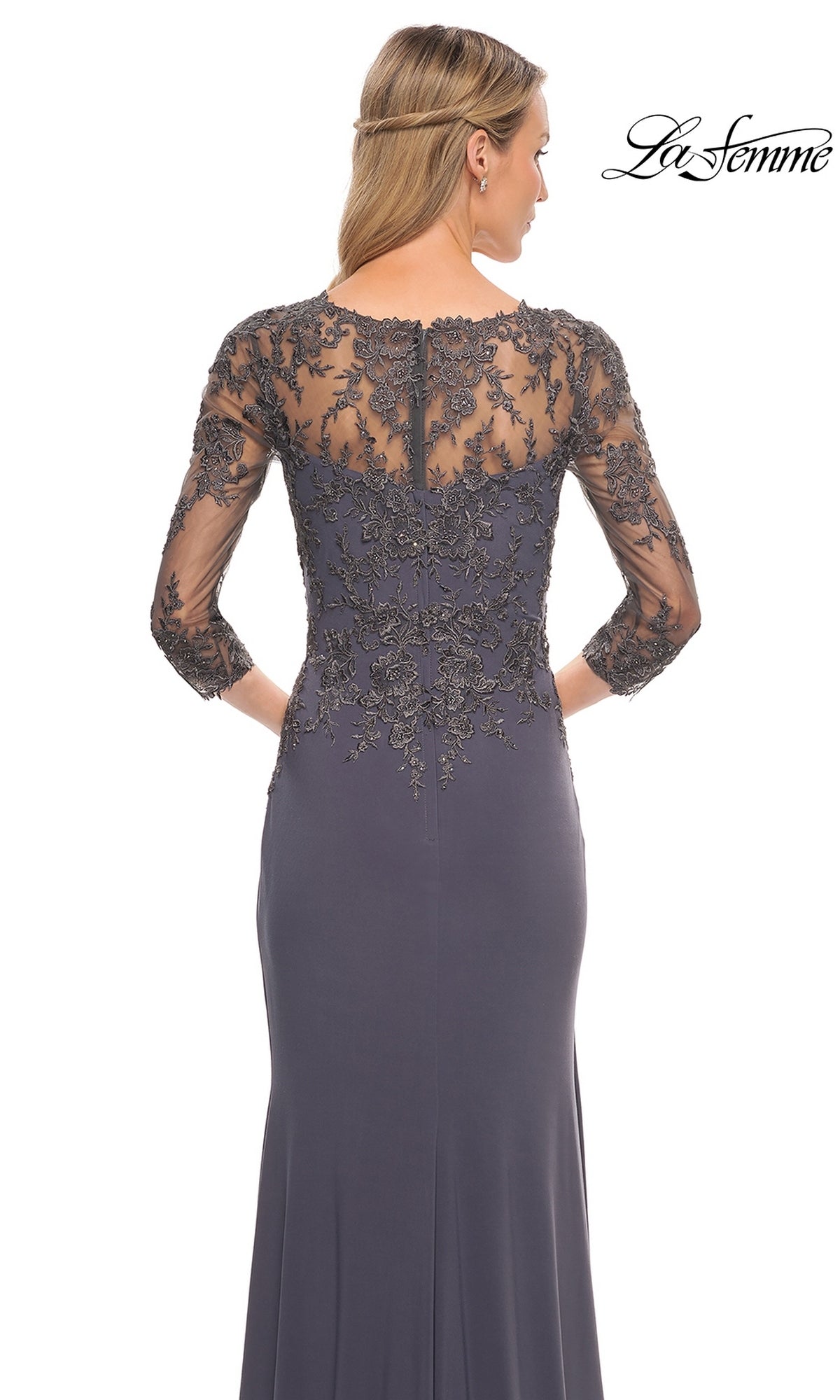 Woman in Long Formal Dress: La Femme 30384 with sheer lace sleeves and back, facing away. “La Femme” logo in top right corner.
