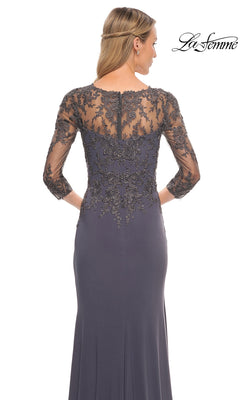 Woman in Long Formal Dress: La Femme 30384 with sheer lace sleeves and back, facing away. “La Femme” logo in top right corner.