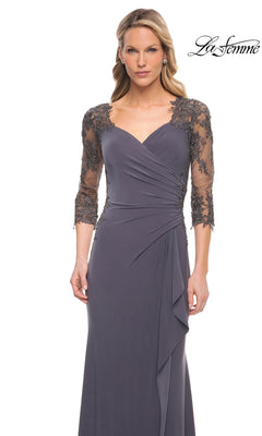 Woman wearing the Long Formal Dress: La Femme 30384, a floor-length slate gray gown with sheer lace sleeves and ruched detailing, stands against a white background.
