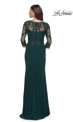 Woman wearing Long Formal Dress: La Femme 30384, a floor-length dark green gown with sheer lace sleeves and back, shown from behind. La Femme logo top right.