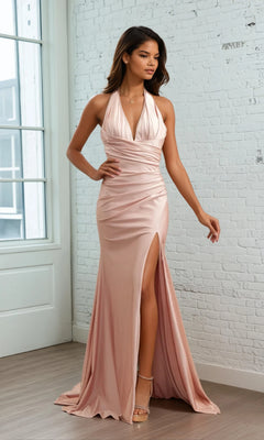 Woman modeling the Amelia Couture 3040 V-Neck Long Halter Prom Dress in blush pink, featuring a deep V neckline and high slit, standing indoors against a white brick wall.
