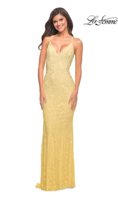 Woman in a La Femme Long Prom Dress with Sheer Beaded Sides, featuring a floor-length yellow lace design, thin straps, and deep V-neckline. She stands smiling; "La Femme" logo appears in top right corner.