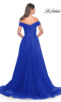 A woman models the La Femme Off-Shoulder Long Prom Ball Gown 30498, a floor-length royal blue dress with a fitted bodice and flowing skirt, elegantly displayed from the back.