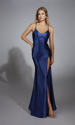 A woman stands against a plain grey background wearing the Aerie Couture 305, a long fitted prom dress featuring blue satin fabric, thin straps, a v-neckline, sleeveless design, and a thigh-high slit.
