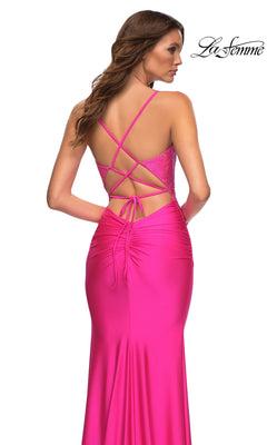 A woman is seen from the back wearing the La Femme Neon Pink Long Prom Dress 30601, featuring crisscross straps and ruching. The "La Femme" logo is displayed in the top right corner.