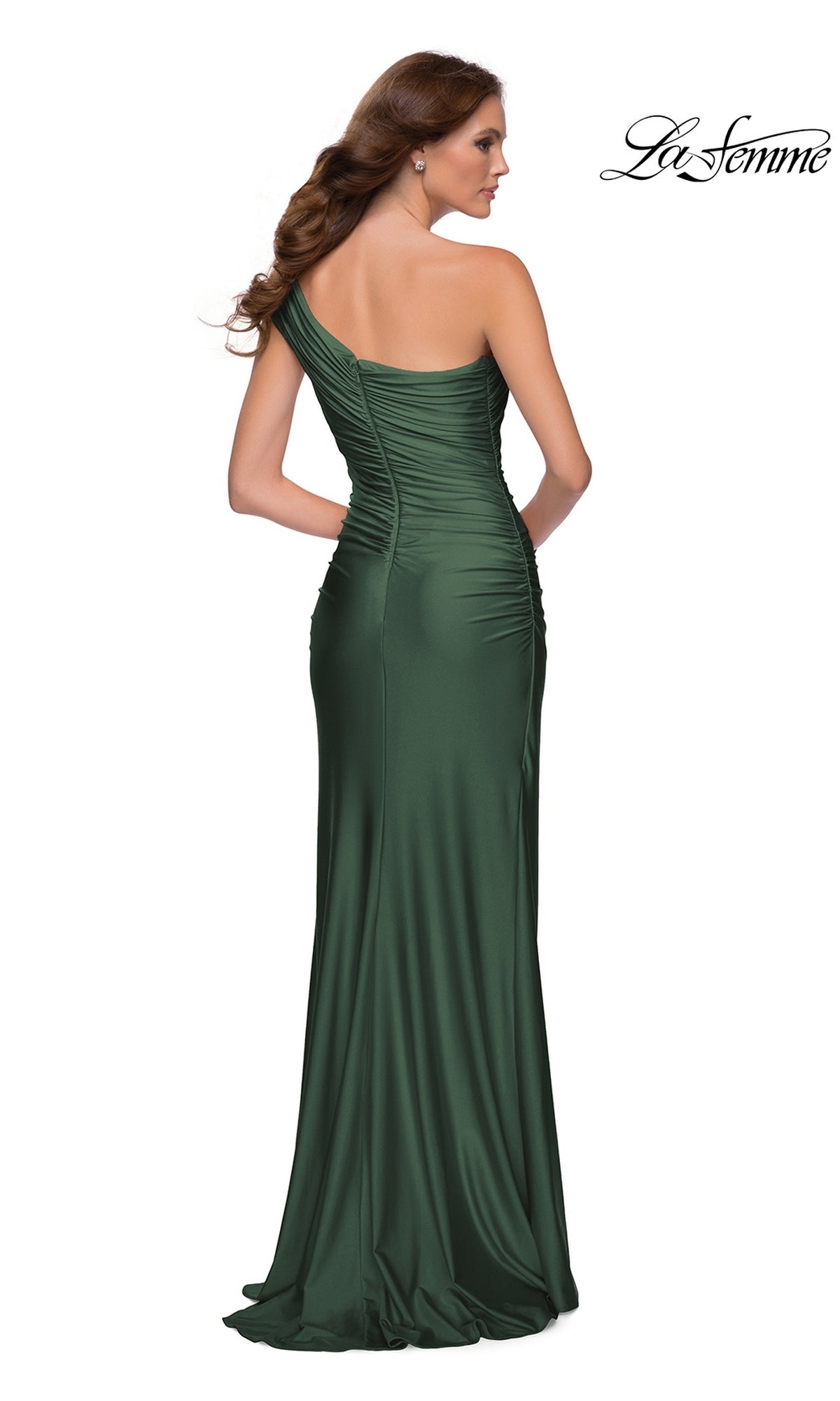 A woman wears the Long Prom Dress: La Femme 30645, a floor-length, dark green, one-shoulder ruched jersey gown with a high-leg slit.