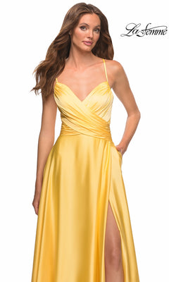 Woman wearing a bright yellow satin Long Prom Dress: La Femme 30662 with a V-neckline, crossover bodice, and a side slit.