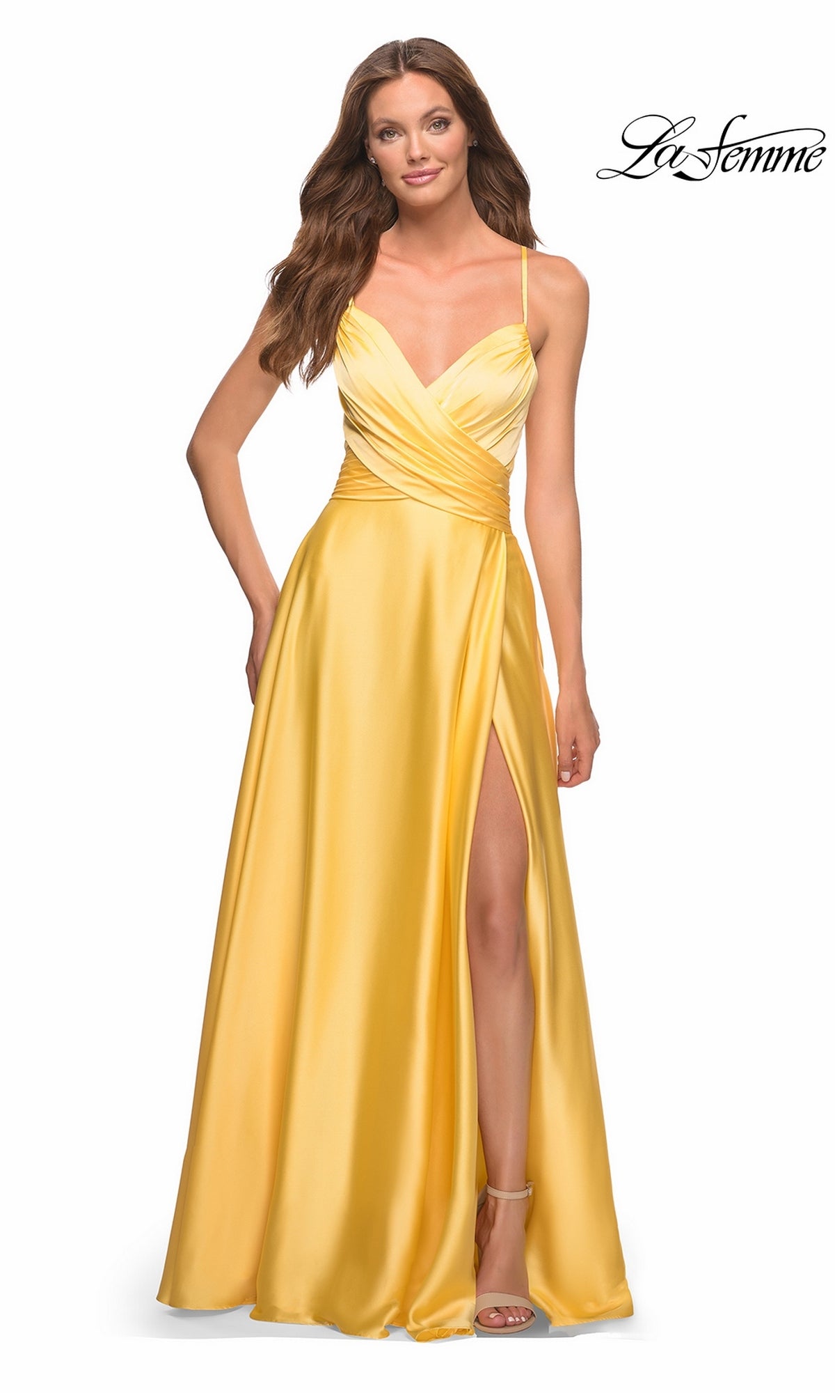 A model wearing a yellow La Femme 30662 A-line satin prom dress with a V-neckline, a wrap-style bodice, and a high leg slit.
