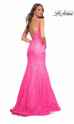 A woman wearing a La Femme 30663 floor-length, hot pink lace mermaid gown with a low back and thin spaghetti straps.