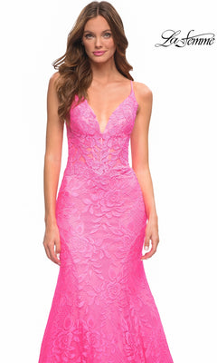 A woman wears a bright, hot pink La Femme 30663 mermaid prom dress in floor-length floral lace with a plunging V-neckline and spaghetti straps.