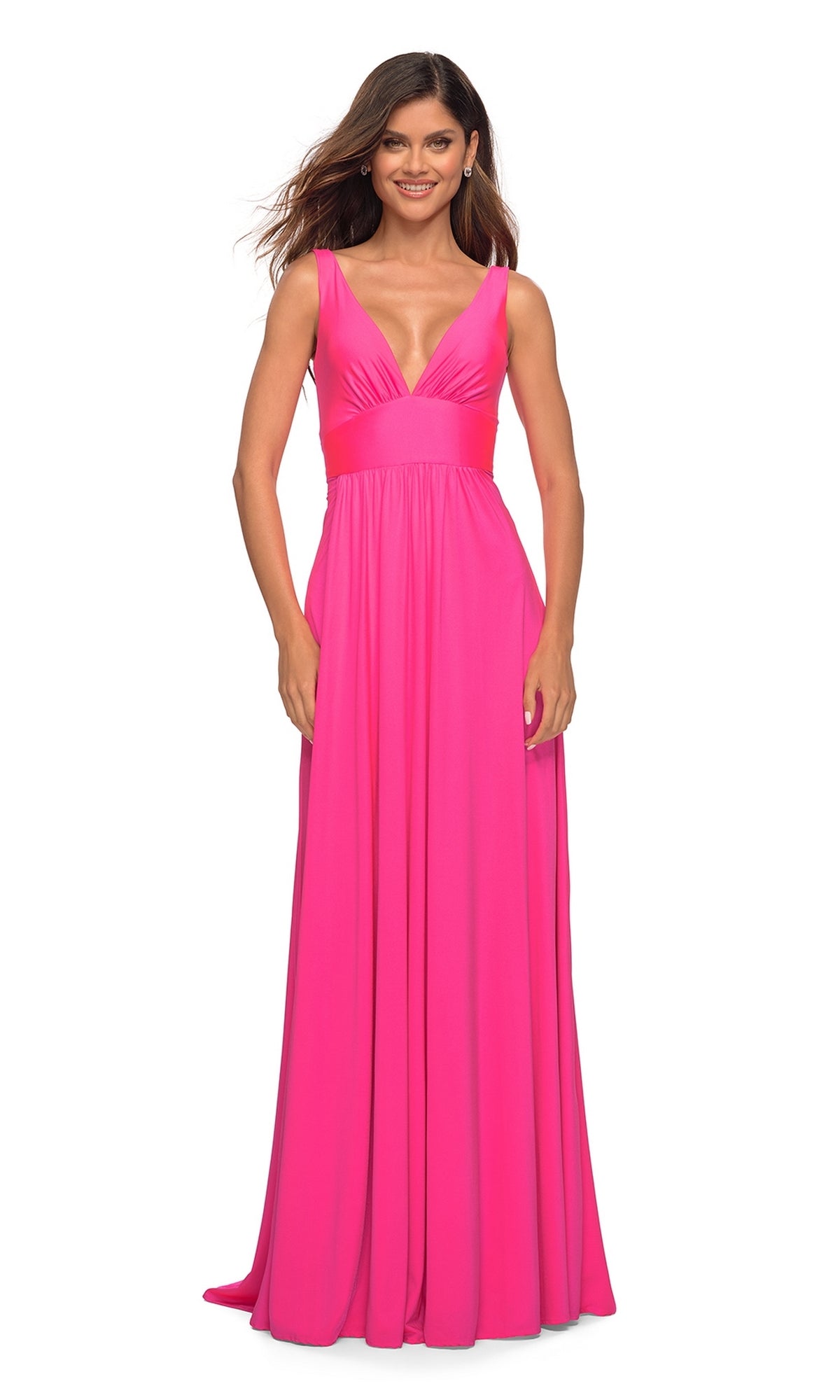 A woman smiles facing forward in the La Femme Neon Pink Long A-Line Prom Dress 30669, featuring a sleeveless design, deep V-neckline, and floor-length silhouette.