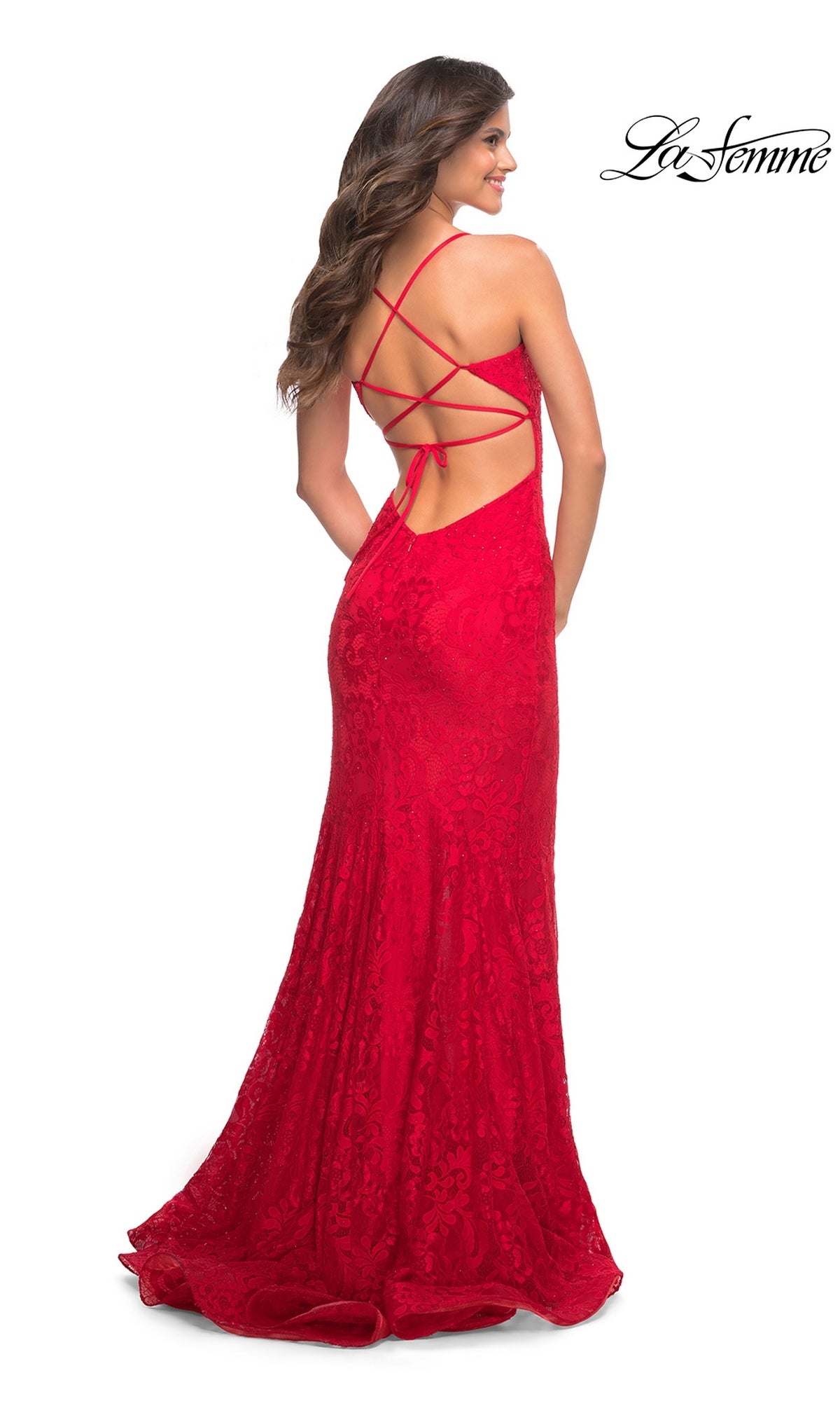 A woman wearing a floor-length red lace Long Prom Dress: La Femme 30671 with a strappy open back.